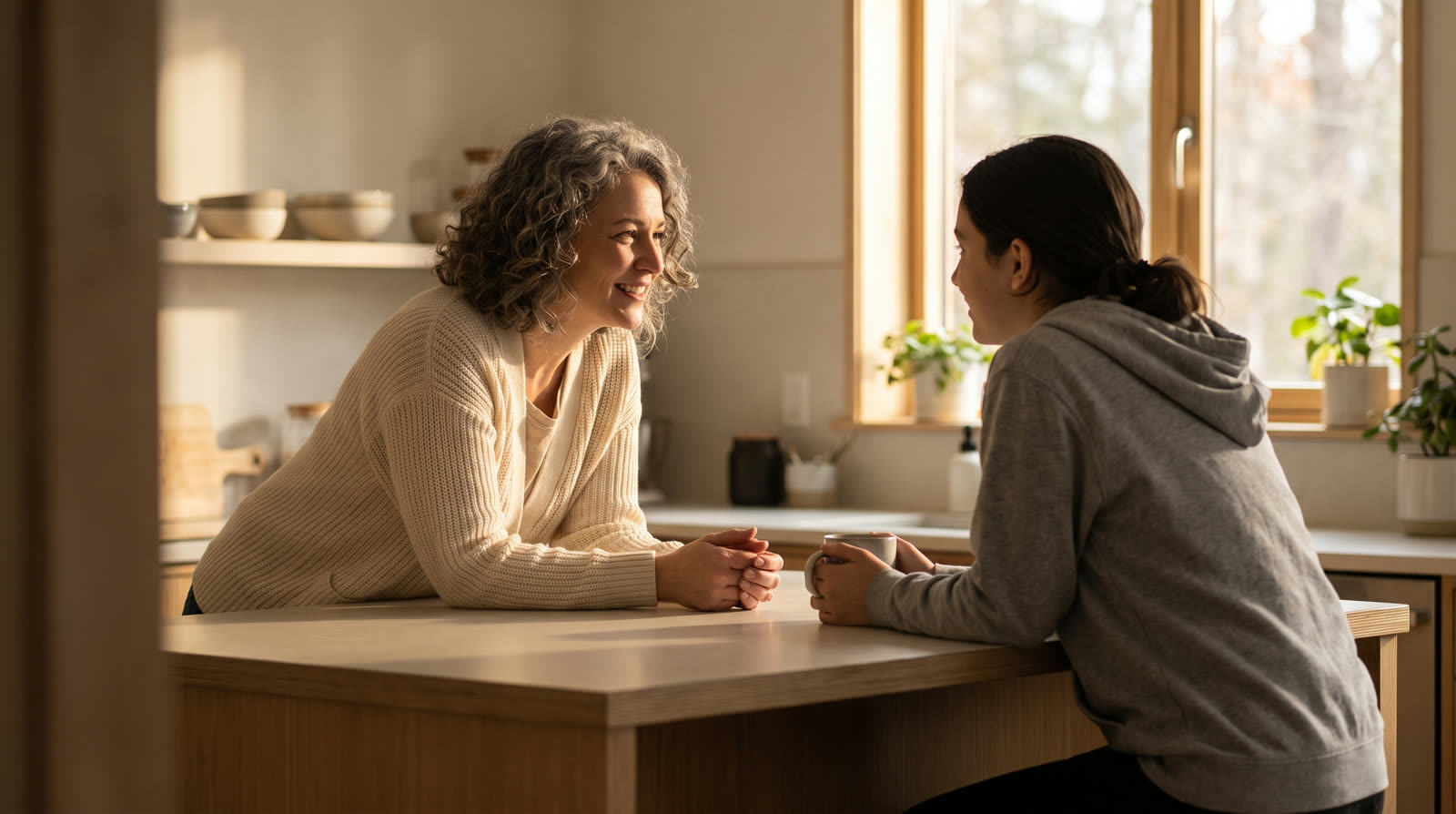 Mother and college-age daughter talking across a kitchen island