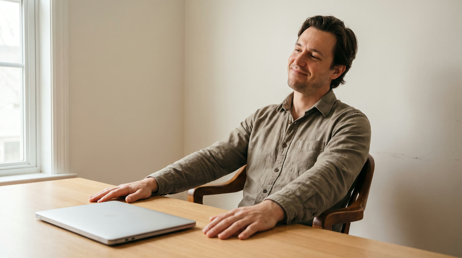 Man leaning back at his desk with a relieved smile