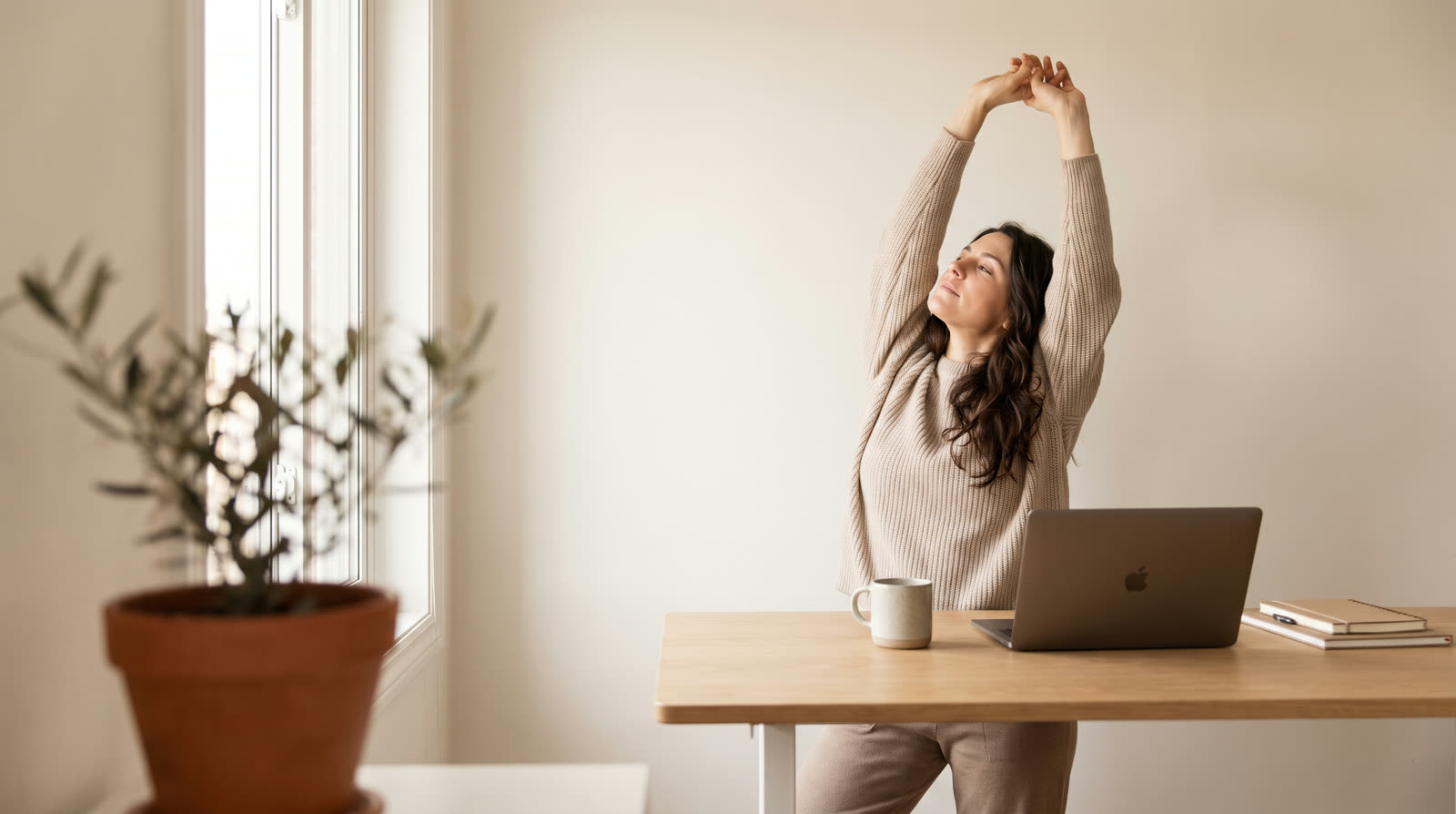 Freelance designer stretching after work at her home studio desk